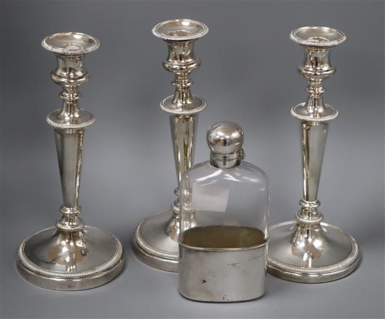 Assorted plated wares to include three candlesticks and a spirit flask